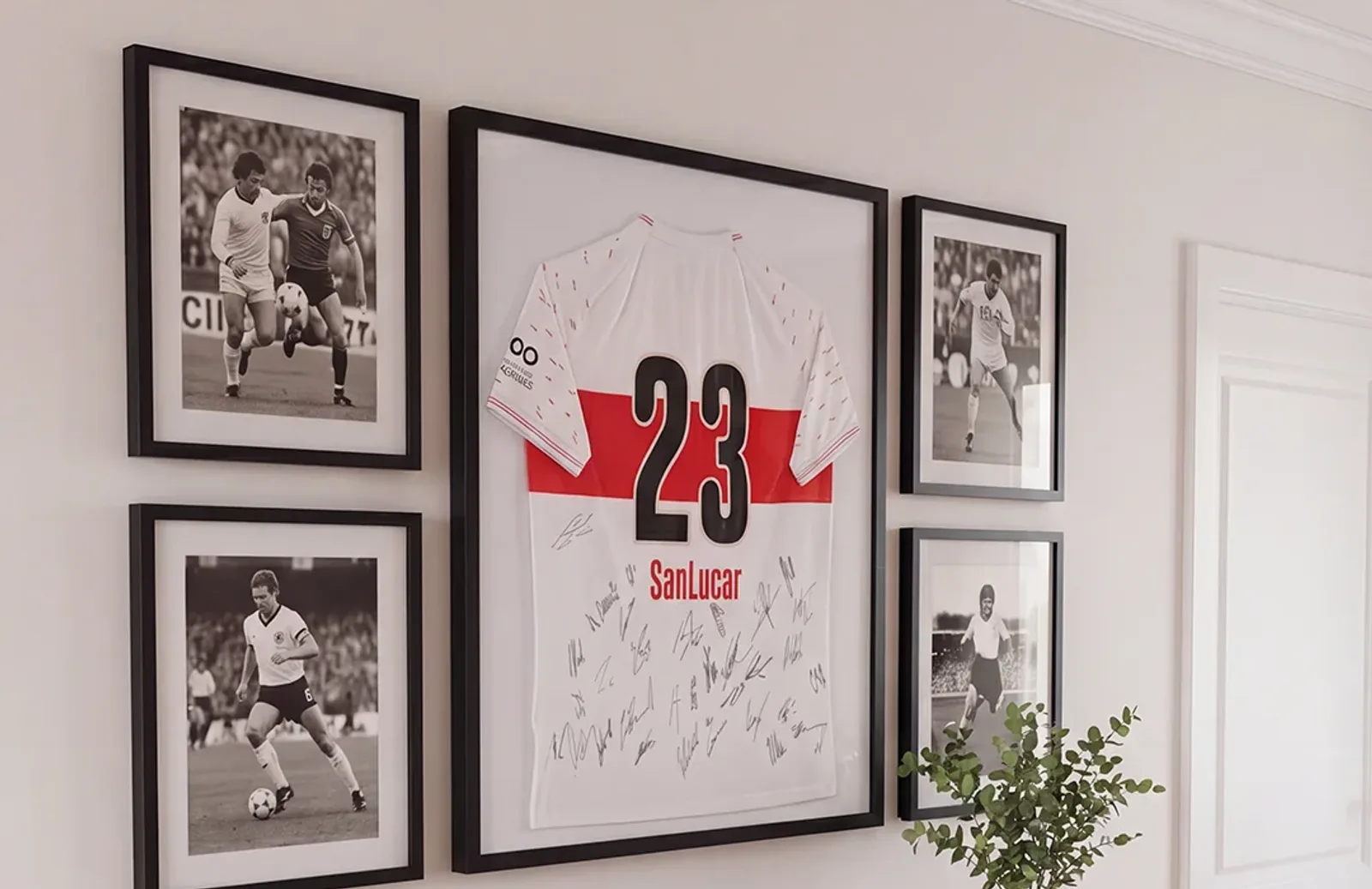 Camiseta firmada en un marco vitrina negro en la pared del salón, flanqueada por fotos en blanco y negro enmarcadas