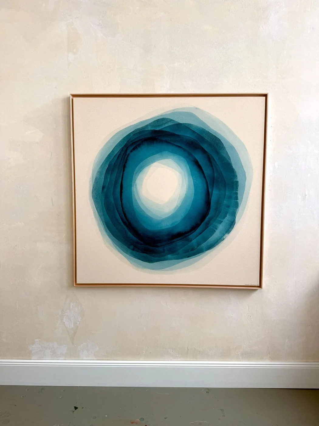 Obra circular de Johanne Bossmann en tonos petróleo y turquesa, en un marco de madera clara