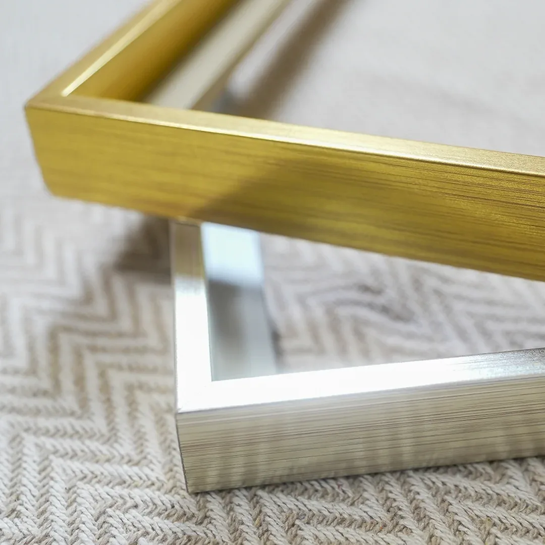 Primer plano de las esquinas en inglete de un marco de aluminio dorado y otro plateado