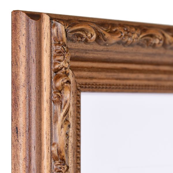 Vista de la esquina de un marco de madera marrón de estilo barroco con una superficie rústica teñida de nogal, ornamentos florales ligeramente brillantes y una moldura de perlas en el borde interior