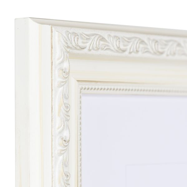 Vista de la esquina de un marco de madera barroco blanco y caprichoso con ornamentos florales y un delicado motivo de perlas