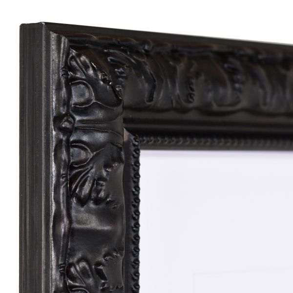 Vista de la esquina de un marco de madera negro con un diseño elegante y barroco y borde de perlas.
