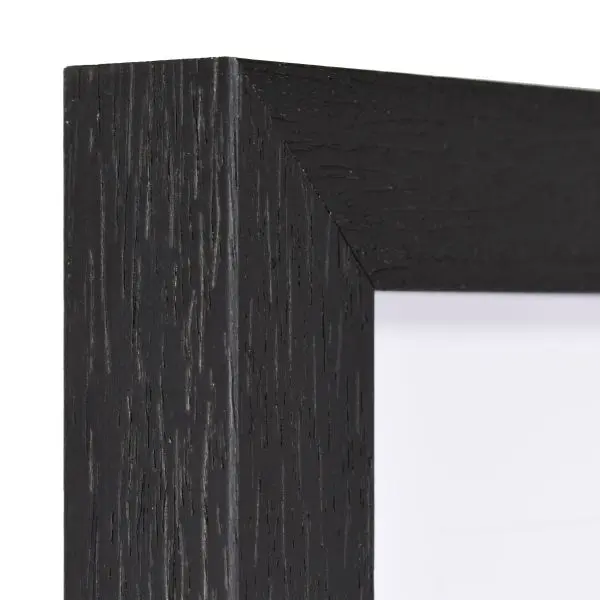 Vista de la esquina de un marco de madera negro, lacado de poro abierto con estructura de madera visible y palpable.
