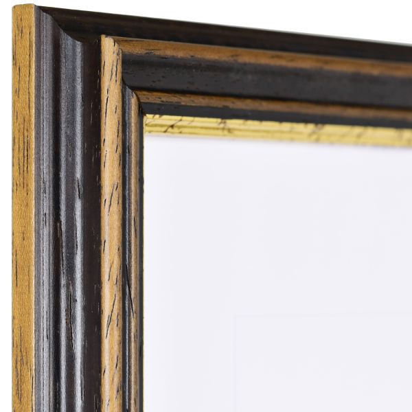 Vista de la esquina de un marco de madera marrón con una moldura cóncava profunda y un borde dorado escalonado