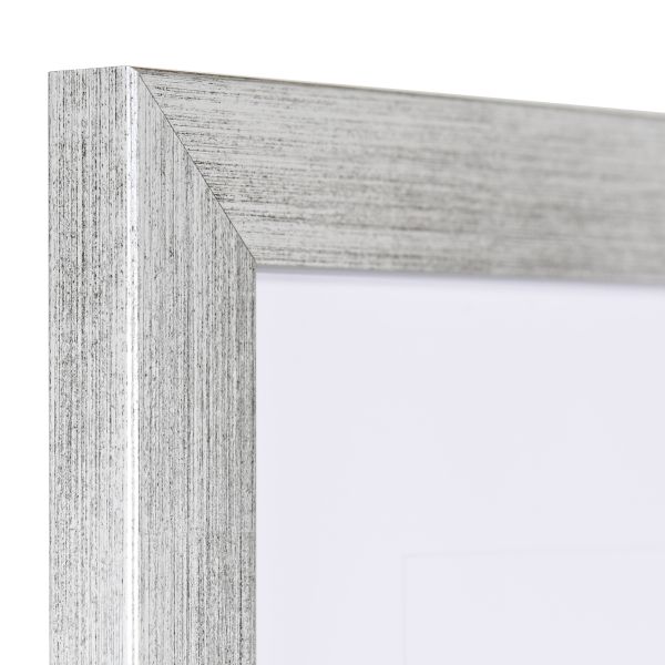 Vista de la esquina de un marco de fotos plateado con estructura de madera visible, superficie lisa y perfil angular y sencillo.