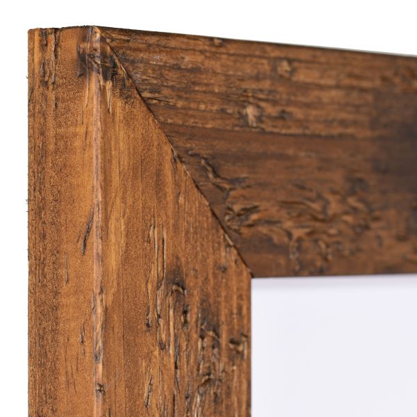 Vista de la esquina de un marco de madera rústico, marrón, con perfil plano rectangular y aspecto envejecido