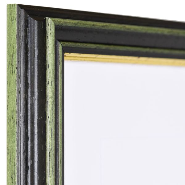 Vista de la esquina de un marco de madera verde, de estilo antiguo, con una profunda moldura cóncava y un borde dorado escalonado
